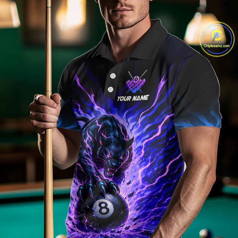 Man wearing a black polo shirt with a panther and pool ball design, holding a pool cue on a billiard table.