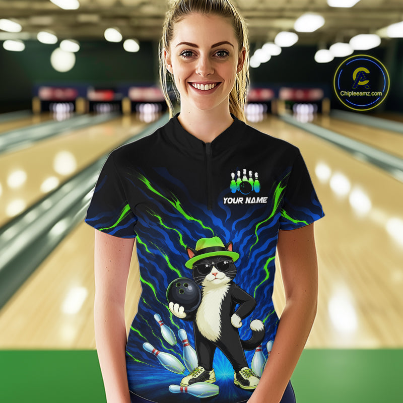 A woman stands in a bowling alley wearing a black short-sleeve bowling-themed t-shirt with a colorful graphic of a cat bowling and the text 'YOUR NAME' and 'CHIPLEMAN'.