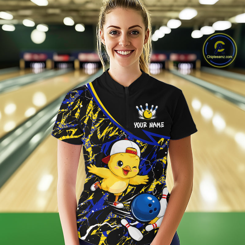 Person wearing a bowling shirt with a cartoon chicken design in a bowling alley.