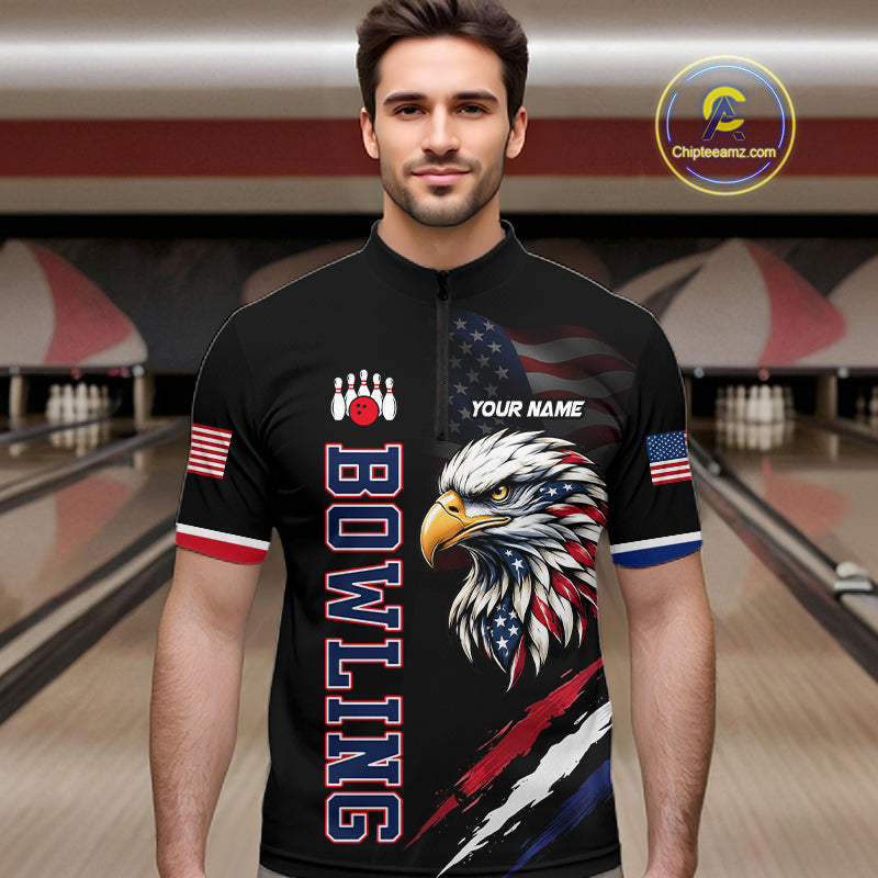 Man wearing a black bowling shirt with eagle design and text in a bowling alley.