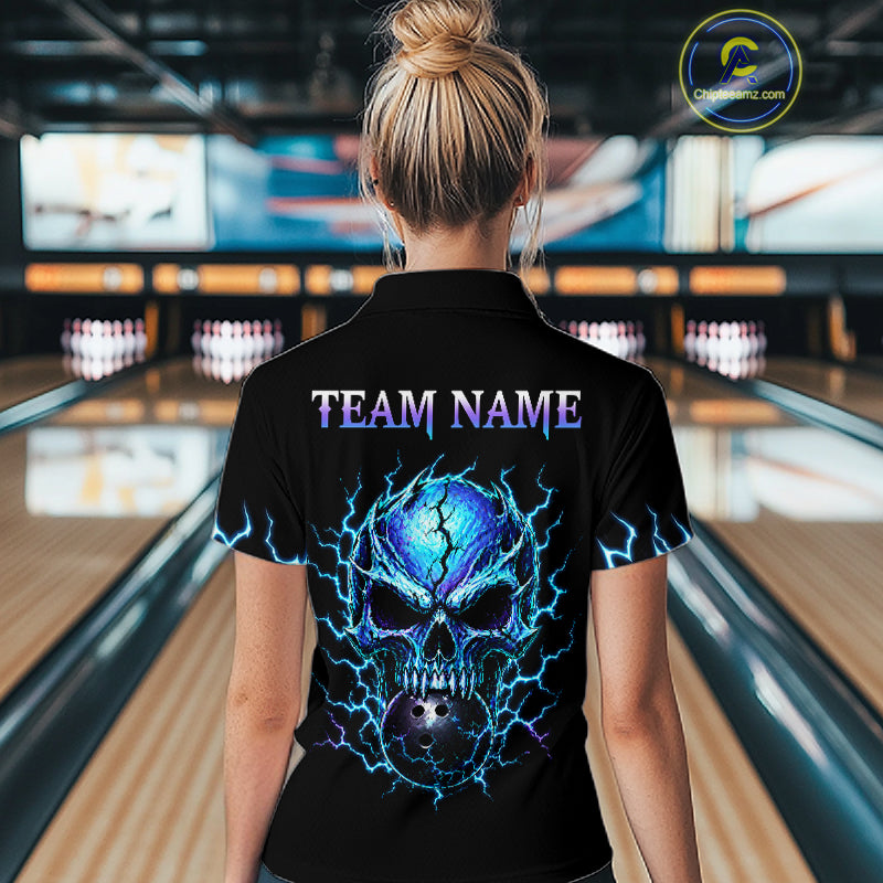 A woman viewed from behind wearing a black short-sleeve polo shirt with a large blue and purple skull graphic and the text 'TEAM NAME' on the back, standing in a bowling alley.
