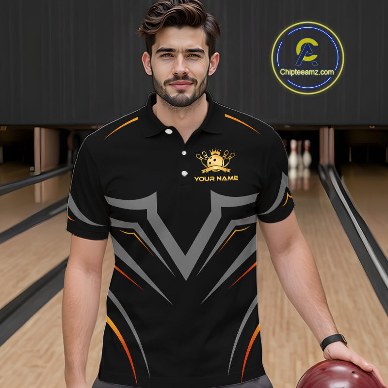 Man wearing a black bowling shirt with a logo and text in a bowling alley.