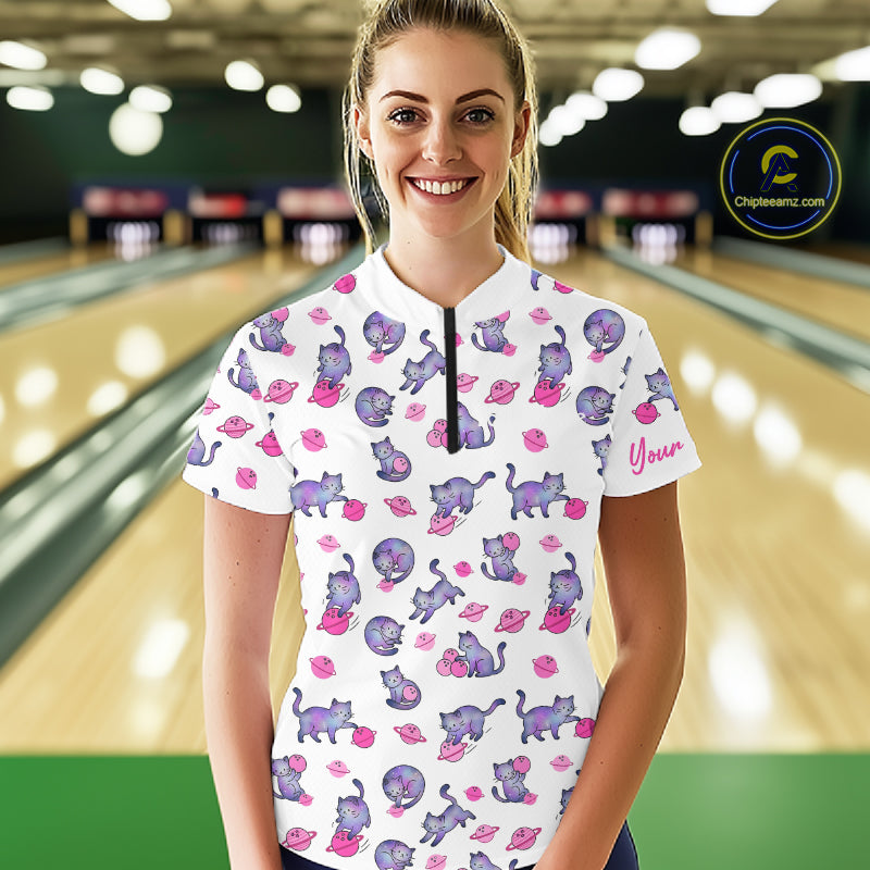 Woman wearing a white bowling shirt with pink cat pattern in a bowling alley.