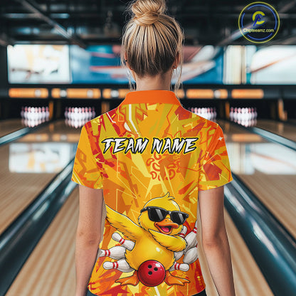 Person wearing a bright yellow bowling shirt with a duck design in a bowling alley.