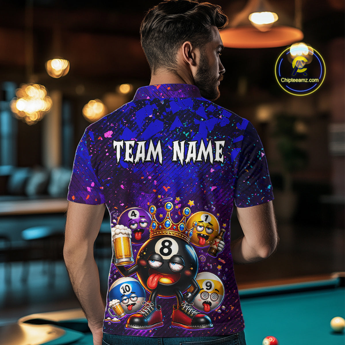A man viewed from behind wearing a custom purple and blue patterned short-sleeve polo shirt with a cartoon 8-ball design and the text 'TEAM NAME' on the back, in a dimly lit pool room.
