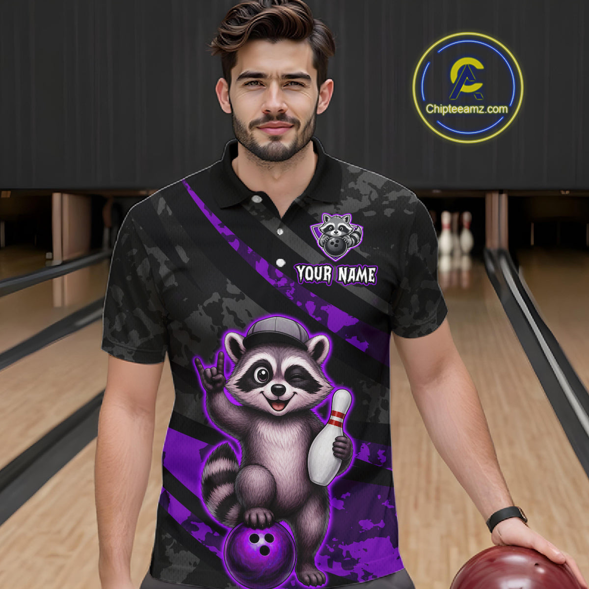 Man wearing a black and purple bowling shirt with a raccoon design on a bowling alley.