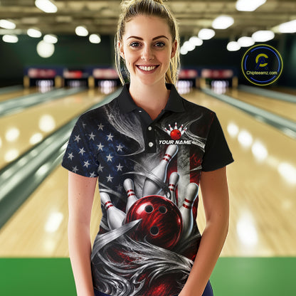 A woman stands in a bowling alley wearing a black short-sleeve polo shirt with a detailed bowling-themed graphic print featuring bowling pins, a red bowling ball, an American flag pattern, and customizable text. 
