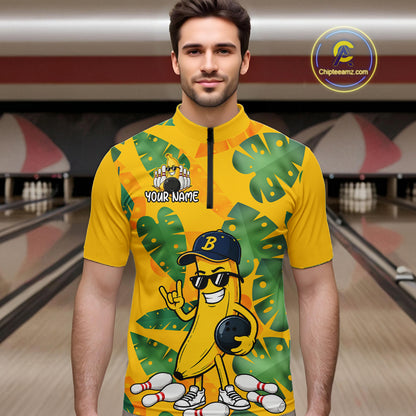 Man in a bowling alley wearing a bright yellow tropical quarter zip shirt with green leaf patterns, custom name text, and a smiling banana mascot holding a bowling ball.