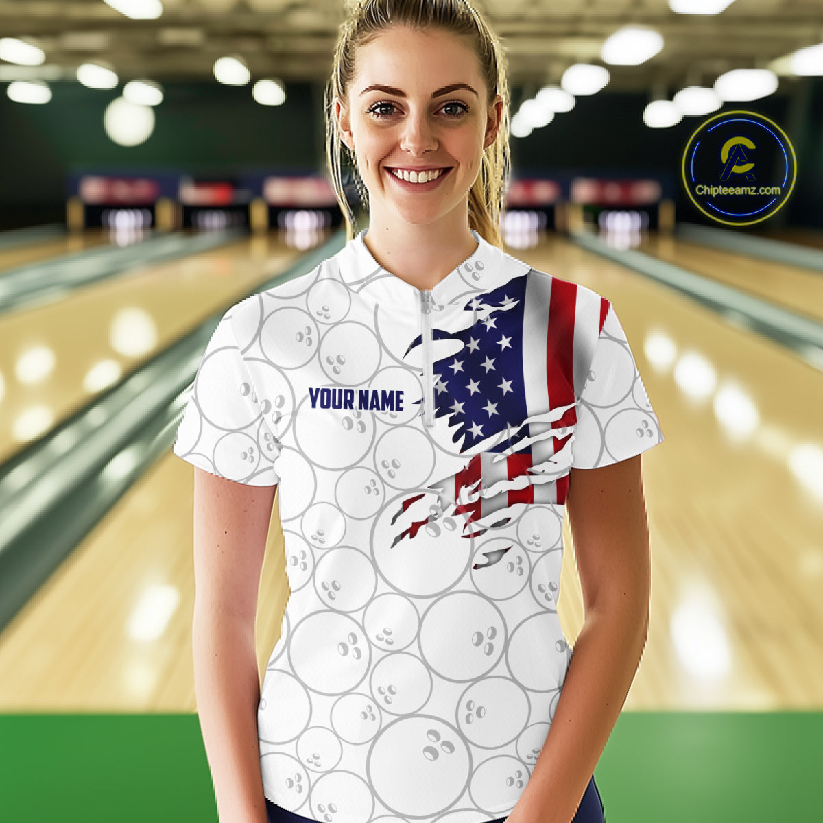 A woman stands in a bowling alley wearing a white short-sleeve polo shirt with a printed bowling-ball pattern and a torn American flag graphic on the right side. The shirt has 'YOUR NAME' printed on the chest.