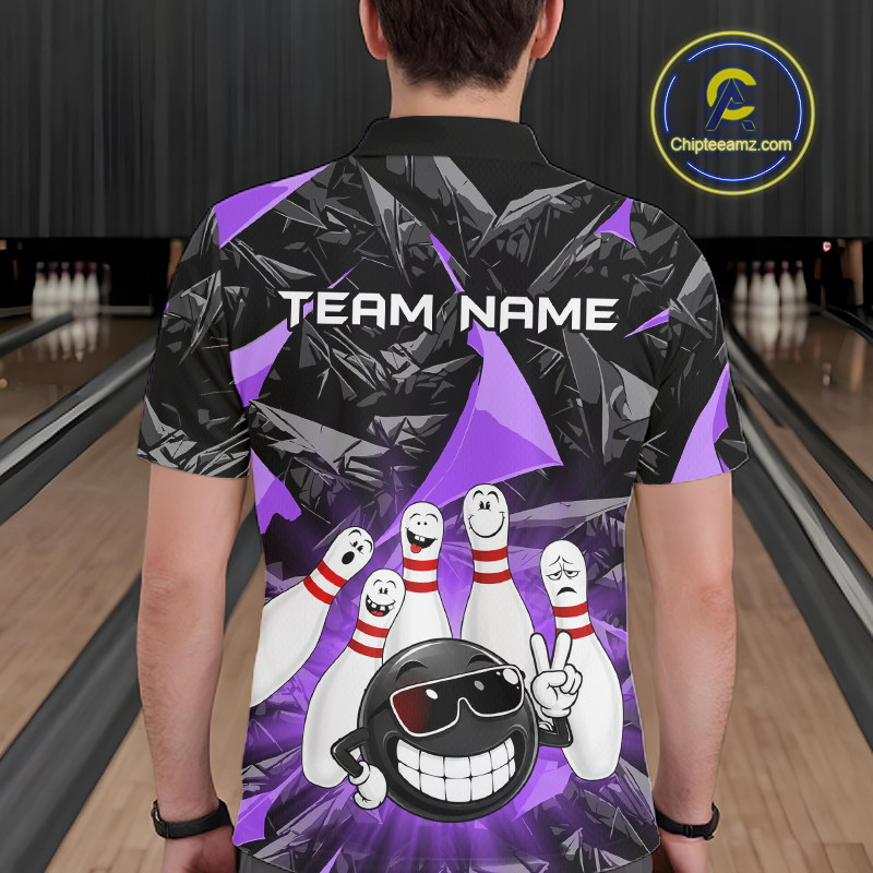A person standing in a bowling alley viewed from behind, wearing a short-sleeve collared shirt with a bold bowling-themed graphic. The shirt has a black and purple geometric background with cartoon bowling pins, a bowling ball, and the text 'TEAM NAME' across the back.