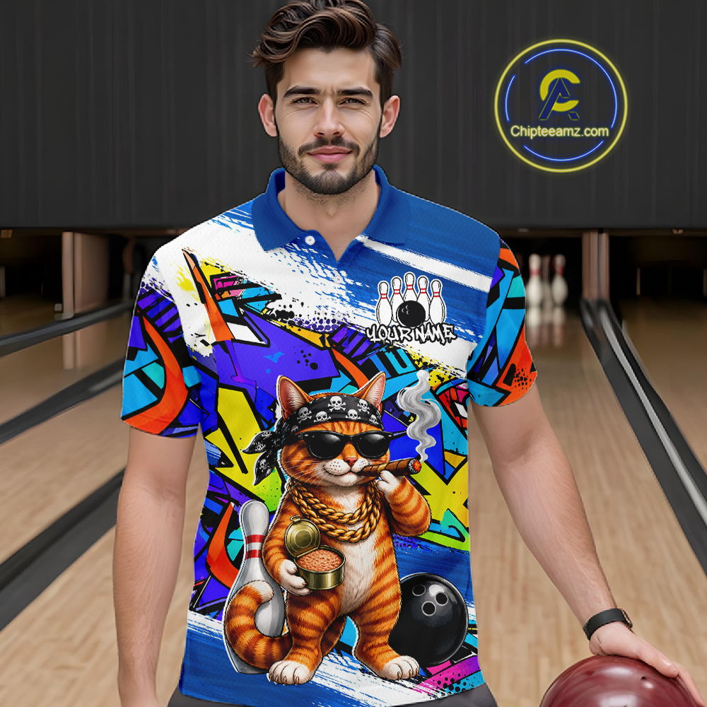 Man wearing a colorful bowling-themed shirt with a cat graphic in a bowling alley.