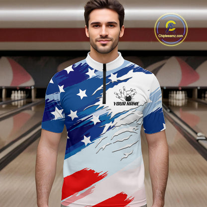 A man wearing a short-sleeve quarter-zip athletic jersey with a patriotic American flag-inspired design in blue, white, and red, standing in a bowling alley. The jersey features white stars on a blue background and red brushstroke stripes on a white background, with a black zipper at the neck and a customizable chest graphic that reads 'YOUR NAME' with bowling pins.