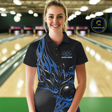 Load image into Gallery viewer, Female model seen from the front in a bowling lane wearing a black polo shirt featuring a blue flaming black bowling ball striking pins in a dynamic sports action design.