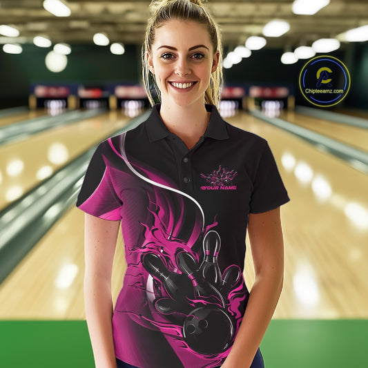 Female model front view in bowling lane wearing black and pink polo shirt with flaming bowling ball hitting pins in dynamic sports action scene.