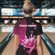 Load image into Gallery viewer, Back view of a black and pink women s bowling quarter zip with breast cancer awareness ribbons, butterfly artwork, and bowling graphics in a bowling venue.