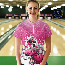 Load image into Gallery viewer, Female model at a bowling lane wearing a pink bowling quarter-zip shirt with a crowned flamingo, cocktail, bowling ball, and paint splatter graphics.