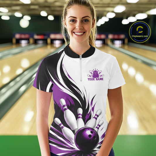 Female model shown from the front wearing a white, black, and purple bowling quarter zip shirt featuring a flaming bowling ball striking pins artwork in a bowling lane.