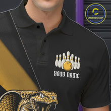 Load image into Gallery viewer, Left chest close-up of a black bowling polo featuring a yellow cobra, bowling ball, and scattered pin artwork.