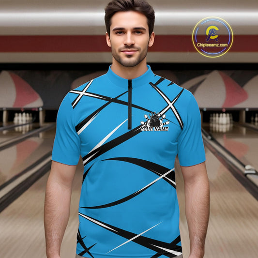Front view of a male bowler wearing a blue, black, and white bowling quarter zip shirt in a bowling alley
