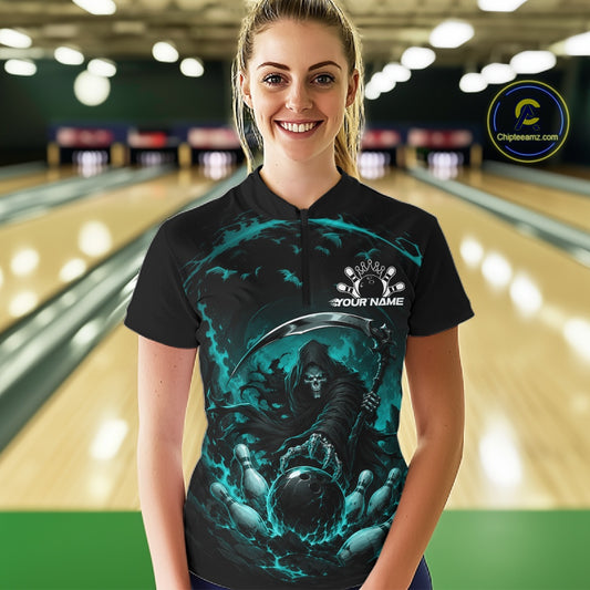 Front view of a female model wearing a black and cyan blue bowling quarter zip shirt showcasing a grim reaper with a blazing bowling ball striking scattered pins amid swirling flames in a bowling lane.