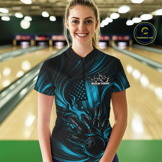 Female model wearing a black and turquoise blue bowling quarter-zip shirt at a bowling lane with patriotic bowling strike artwork and American flag accents.
