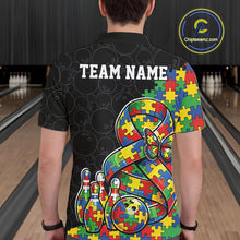 Load image into Gallery viewer, Male model at a bowling lane, back view of black polo shirt showcasing autism awareness ribbon with puzzle fill, butterfly, and bowling ball hitting pins