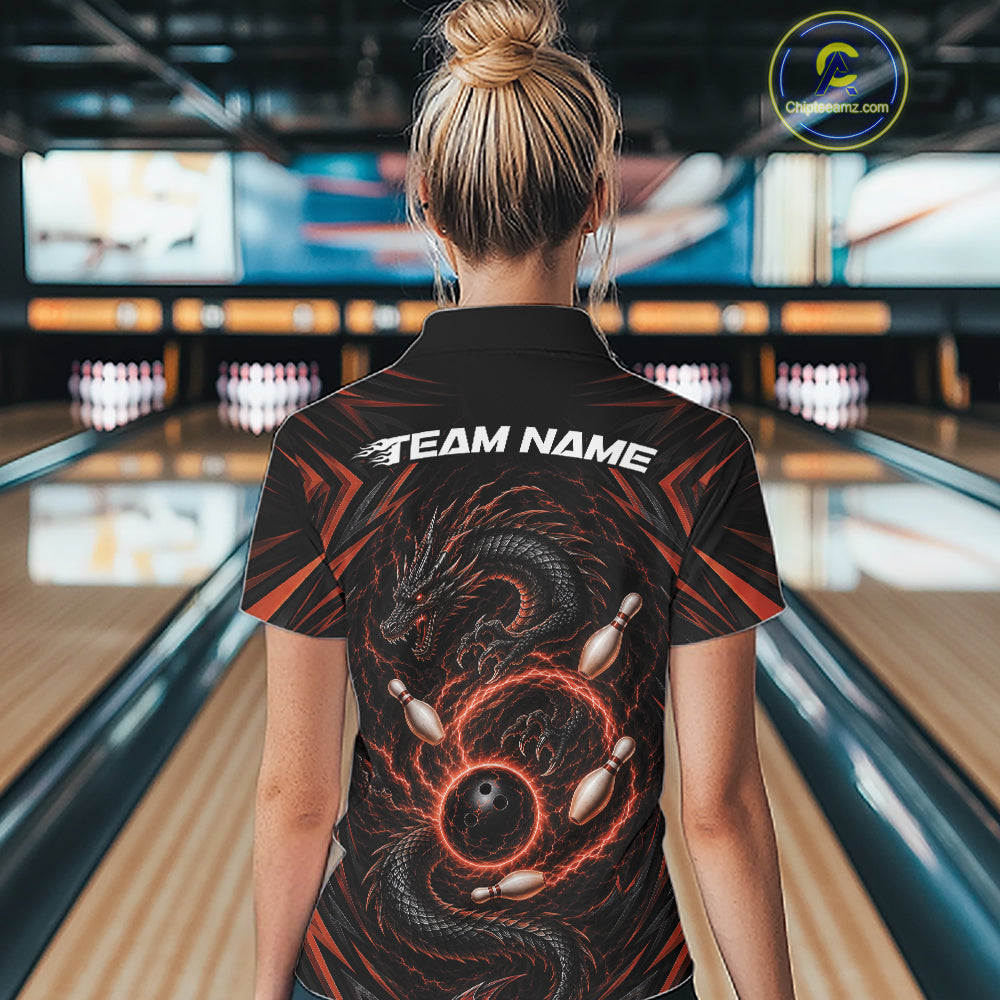 A woman viewed from behind wearing a black bowling-themed short-sleeve collared shirt with a red and black dragon graphic and white 'TEAM NAME' text on the back, standing in a bowling alley.