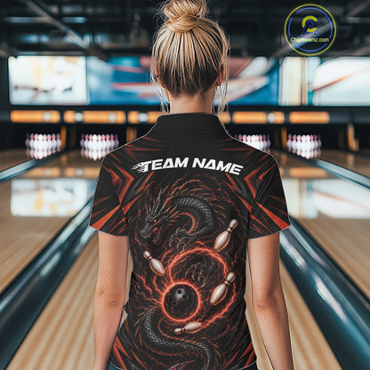A woman viewed from behind wearing a black bowling-themed short-sleeve collared shirt with a red and black dragon graphic and white 'TEAM NAME' text on the back, standing in a bowling alley.