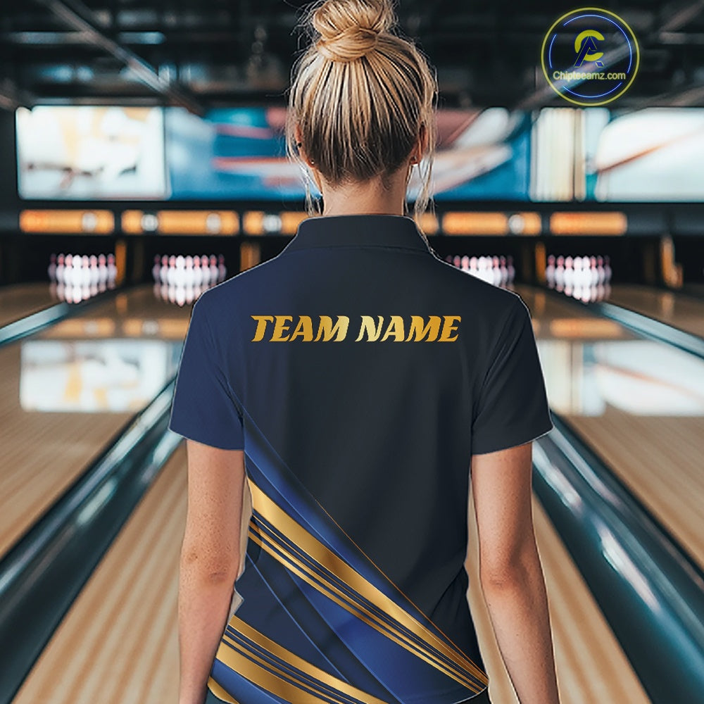 A woman viewed from behind at a bowling alley wearing a dark navy short-sleeve collared shirt with gold 'TEAM NAME' text on the back and diagonal gold and navy stripes near the lower back. Bowling lanes and pins are blurred in the background.