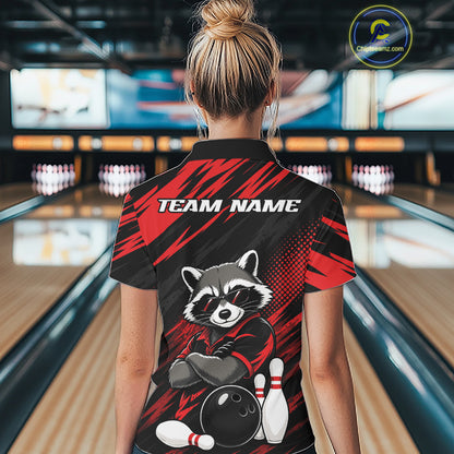 A woman viewed from behind wearing a black and red bowling-themed short-sleeve polo shirt with a raccoon graphic and 'TEAM NAME' text, standing in a bowling alley.