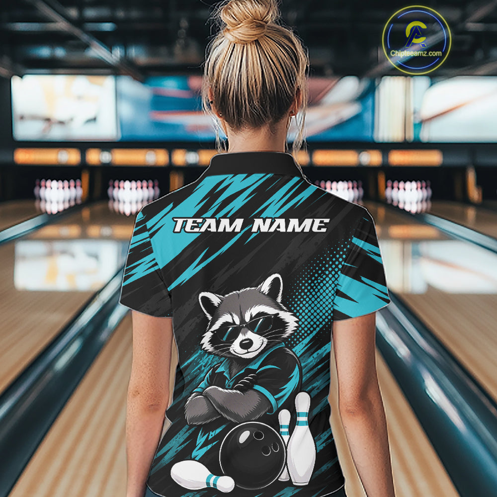 A woman viewed from behind wearing a bowling-themed short-sleeve polo shirt in a bowling alley. The back of the shirt features a raccoon graphic with bowling pins and ball, the text 'TEAM NAME', and a teal and black patterned design.