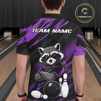 A person shown from the back wearing a short-sleeve polo bowling shirt in a bowling alley. The shirt is black with bold purple graphic stripes and a large raccoon illustration sitting on bowling pins, with the text 'TEAM NAME' across the upper back.