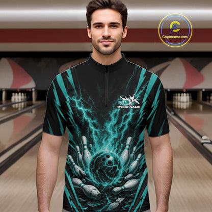 A man wearing a black short-sleeve quarter zip bowling shirt with a teal and black lightning-bolt and bowling pins graphic, standing in a bowling alley. 