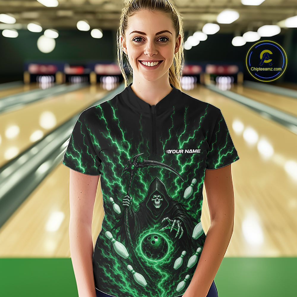 A woman stands in a bowling alley wearing a black short-sleeve bowling shirt with a green and black grim reaper graphic and the text 'YOUR NAME' 
