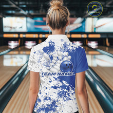 Load image into Gallery viewer, Back view female model in bowling venue wearing white polo with blue and white splatter design, standing near bowling lanes