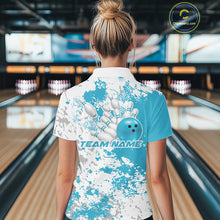 Load image into Gallery viewer, Back view female model in bowling alley wearing white polo with teal blue and white splatter design, relaxed stance near bowling lane