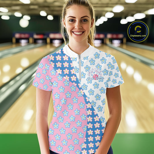 Front view of a female model at a bowling lane wearing a white quarter-zip shirt with white, blue and pink floral pattern and elegant sporty design accents.