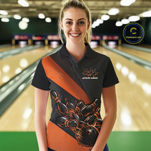 Load image into Gallery viewer, Female model front view in a bowling lane wearing a black and orange polo shirt featuring flame bowling ball striking pins in dynamic sports artwork.
