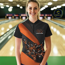 Load image into Gallery viewer, Female model front view at bowling lane wearing black and orange quarter zip shirt with fiery bowling ball knocking down pins illustration