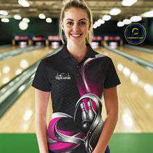 Load image into Gallery viewer, Female model in a bowling alley wearing a black and pink polo shirt with honeycomb texture and a heart-framed bowling strike graphic.