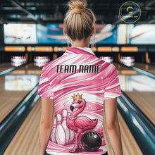 Load image into Gallery viewer, Back view of a female model in a bowling alley wearing a pink polo shirt featuring a crowned flamingo beside bowling pins and a bowling ball.