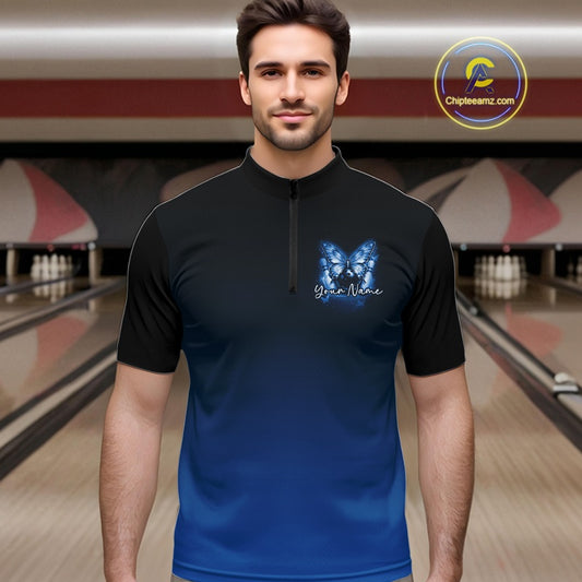Male model at a bowling lane wearing a blue bowling quarter-zip shirt with glowing butterflies, a bowling ball centerpiece, and fallen pin graphics.