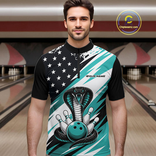 A man stands in a bowling alley wearing a black, white, and blue bowling shirt with stars, diagonal stripes, a cobra, pins, and an blue ball.