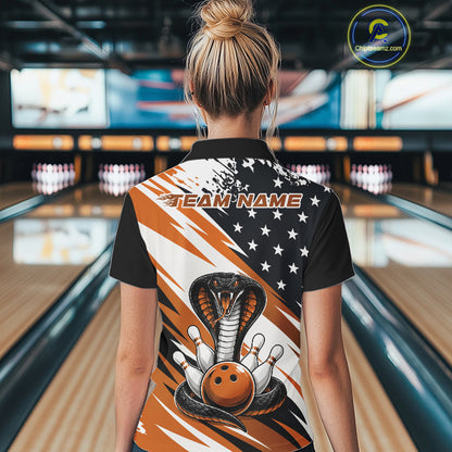 Back view of a woman in a bowling alley wearing a black, white, and orange american flag cobra-themed shirt with “Team Name” across the shoulders.