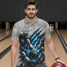 Load image into Gallery viewer, Front view of a male model wearing a gray bowling polo shirt showcasing a dramatic blue bowling ball striking pins graphic with claw-mark artwork in a bowling lane.