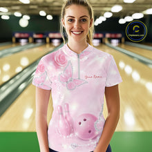 Load image into Gallery viewer, Female model wearing a bowling quarter-zip shirt at the bowling lane with pink glitter butterfly artwork, roses, bowling pins, and a bowling ball on the front.