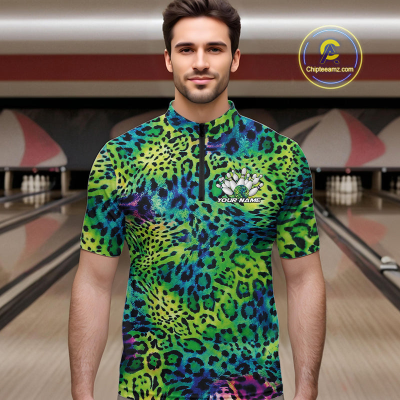 Man in a bowling alley wearing a blue, green, and black leopard-print bowling quarter zip shirt with “Your Name” and a bowling pins graphic on the chest.
