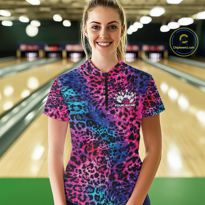 Smiling woman in a bowling alley wearing a purple, blue, and black leopard-print bowling quarter zip shirt with “Your Name” and a bowling pins graphic on the chest.
