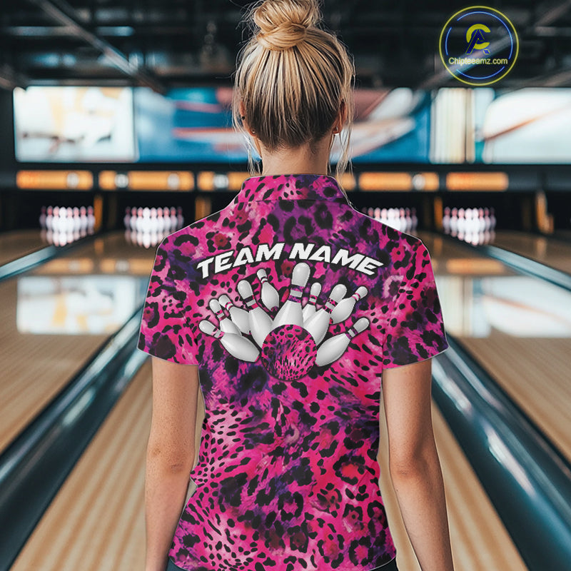 Back view of a woman standing at a bowling alley, wearing a gold, brown, and black leopard-print bowling polo with “Team Name” and bowling pins on the back.
