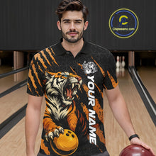 Load image into Gallery viewer, Male model wearing a black and yellow bowling polo shirt at a bowling lane, showcasing a roaring tiger holding a yellow bowling ball with orange claw-stripe graphics and a geometric background pattern.